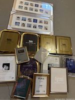 Overview of assorted picture frames including multiple solid brass gold-tone frames and two large white multi-photo frames with sample photos.