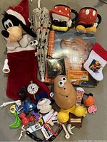 Overview of various Disney-themed items showing plush stocking, mugs, photo album and small toys