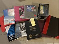 Lot of assorted notebooks, binders, and pen set displayed on a beige floor