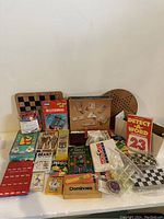 Lot of varied travel games and boards including Guess Who, Mastermind, Dominoes, and others, all arranged together showing packaging and games