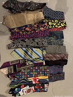 Photo showing an assortment of 16 vintage silk ties arranged on floor with diverse patterns and colors.