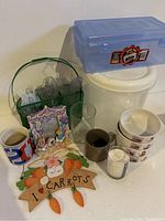 Overall view showing mugs, glass, decorative picture frame, plastic container, and wooden sign with carrots.
