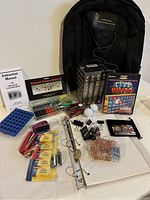 Photo of all items including backpack, molecular model kit, DVDs, office supplies, bingo game, golf balls, copper wire, and instruction manual.