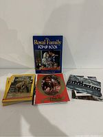Lot of mixed magazines and books including 'The Royal Family Pop-Up Book' with a blue cover, National Geographic magazines and a souvenir program with horse racing theme.