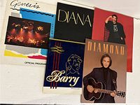 Full lot of 5 music concert programs and a book displayed together on white surface.