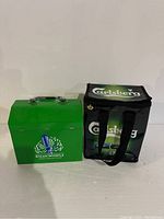 Front view of green Steam Whistle metal cooler and black Carlsberg cooler bag side by side