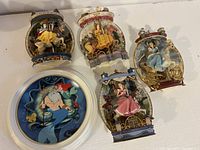 Overview photo showing four 3D figurine Disney princess plates (Snow White, Belle, Cinderella, Aurora), and one round flat plate with Ariel and King Triton artwork.