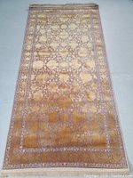 Full view of the machine made rug showing the overall rectangular shape, intricate floral and ornamental pattern in gold and beige colors.