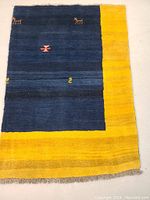 Full view of rectangular Gabbeh rug showing the main blue field with a yellow border and abstract geometric motifs.