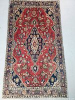 Full front view of rug showing red central field, navy blue corners, floral pattern and border.