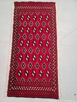 Full view of the Persian Turkmen rug featuring red geometric pattern and border design