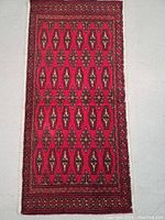 Full view of the hand knotted Turkman wool rug showing the red field with geometric patterned motifs and intricate borders.