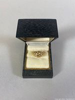 Ring in black jewelry box showing pierced gold design