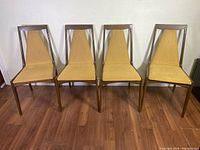 Front view of all four walnut dining chairs arranged side by side.