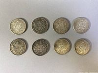 Eight Canadian sterling silver 50 cent coins laid out on a surface, showing the heraldic crest design on one side.