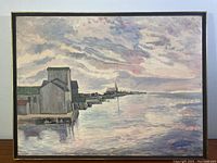 Full front view of framed oil painting featuring waterfront buildings, water reflections and sky.