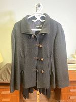 Full view of black textured wool/silk jacket with distinctive knotted buttons and collar, labeled Giorgio Armani