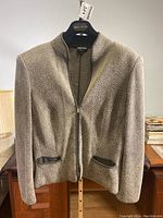 Light jacket front view showing beige and taupe diamond pattern, zipped closure, and two welt pockets.