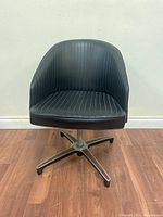 Front view of the black bucket swivel chair showing vertical pinstripe upholstery and metal base.