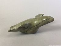 Side view of the greenish polished soapstone bird sculpture on a neutral background.