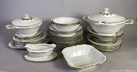 Wide view of dishes including covered tureens, bowls, gravy boat, and plates stacked