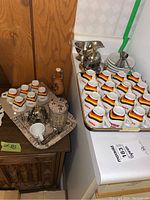 Photo of the coffee and espresso cup set arranged on trays, including cups, saucers, spoons, creamer, sugar bowl, and coffee canister.