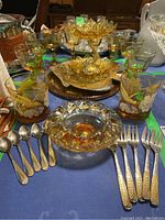 Full set showing rocks glasses, fruit nappies, trivets, ashtray, and flatware on a table.
