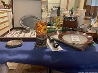 Wide shot showing ice bucket, plates, glass side plates, metal coasters and trays arranged on table.