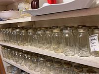 Shelves filled with clear quart size glass canning jars with metal screw lids, some branded Ball and Mason.