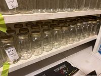 Shelf of clear quart Mason canning jars with gold metal lids, stacked in rows.