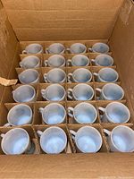 Box containing 24 milk glass mugs arranged in a 4x6 grid with cardboard dividers.