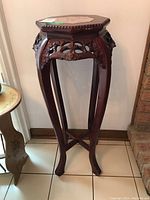 Full view of the wood plant stand with curved legs and carved floral details.