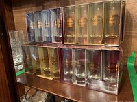 Photo shows multiple sets of shot glasses in original boxes with branding Drambuie, Tia Maria, Cointreau, and Kahlua in gold print.