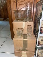 Collection of glassware on stacked cardboard boxes showing ice bucket, pitcher, and glasses