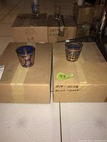 Two cardboard storage boxes each topped with a decorative glass tumbler