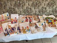 Overview of multiple folded vintage linens with colorful prints including ballerinas, poodles, British guards, and cowboys.