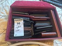 Photo showing maroon faux leather storage case filled with assorted wallets in various colors and finishes.