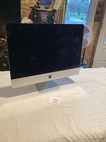 Front view of Apple monitor on table showing black screen and Apple logo below the display