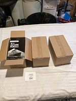 Three cardboard boxes on a table, one open revealing packs of Pencil Buddies Artist Sketching Pencils inside.