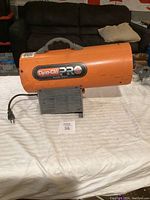 Side perspective of the orange Dyna-Glo Pro heater showing the brand label with 40,000 BTU marking, gray handle, power cord, and metal base.