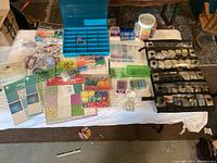 Top-down view of a table with assorted beads, craft papers, and plastic organizers containing jewelry making supplies