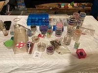 Overview photo showing a variety of jewelry making supplies on a table, including plastic containers, beads, small bags, and other components in assorted colors.