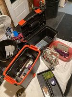 Overview of multiple large plastic storage bins and pink container filled with various jewelry making supplies on a table.