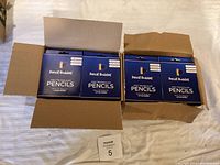 Open box showing 12 packs of Pencil Buddies Kids Triangular Pencils, blue boxes.