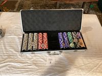 Full view of poker chip set inside an open aluminum carrying case revealing the chips arranged in color groups.