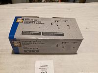 Box of Power Fist Dual Pulley Lift on table, showing front and side with specifications and product illustration