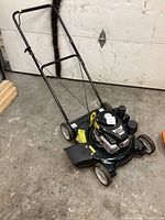 Full view of green Bolens push mower with black engine and white wheels; folded handlebar visible