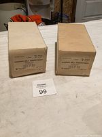 Two off-white cardboard boxes labeled 'Millers Falls Sanding Belt Assortment No. 8410 4" x 21"', placed on a white surface. Each box contains sanding belts of different grits.
