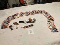 Wide shot showing collection of sports cards arranged in a semi-circle with various jewelry and watches placed in the center.