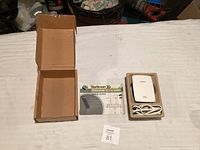 Linksys RE4000W WiFi range extender device in original molded packaging with power cable and instruction manual, and empty opened cardboard box.